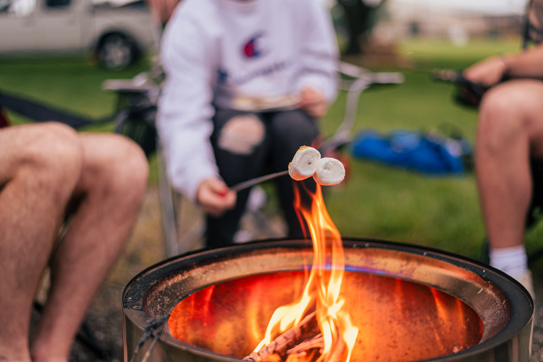 Young adults roasting marshmallows on camp fire