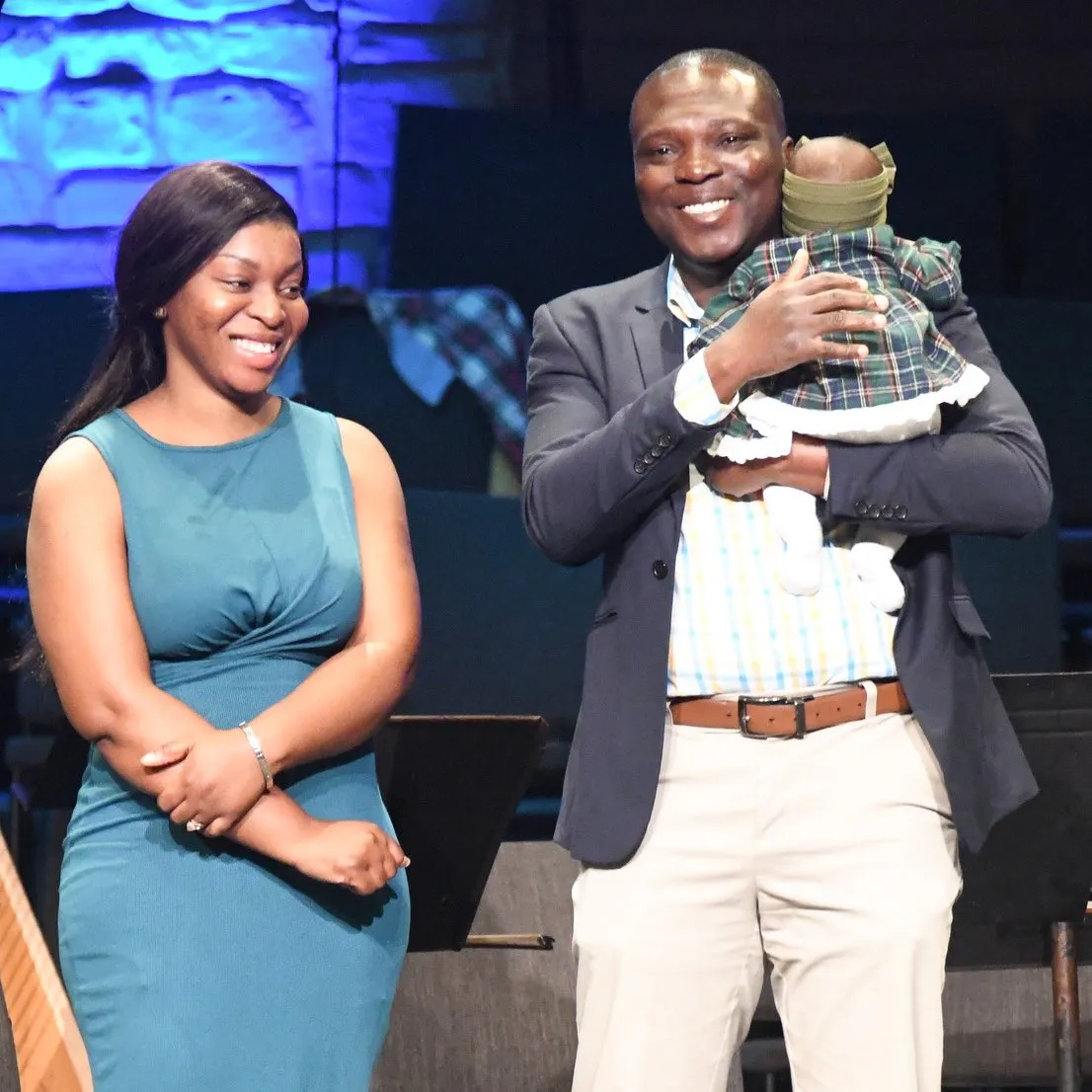 Baby dedication. Couple holding baby on stage.
