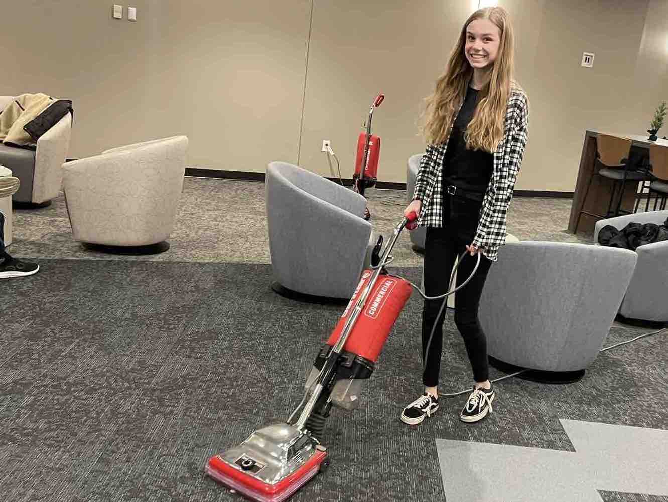 students serve Girl vacuuming church lobby floor